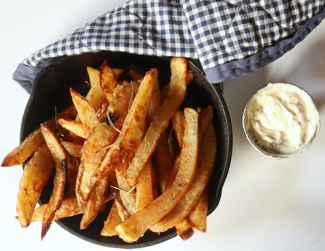 A small cast iron frying pan filled with french fries