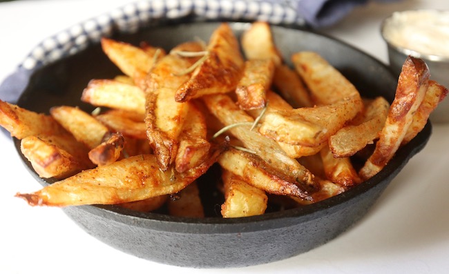 A small cast iron frying pan filled with french fries