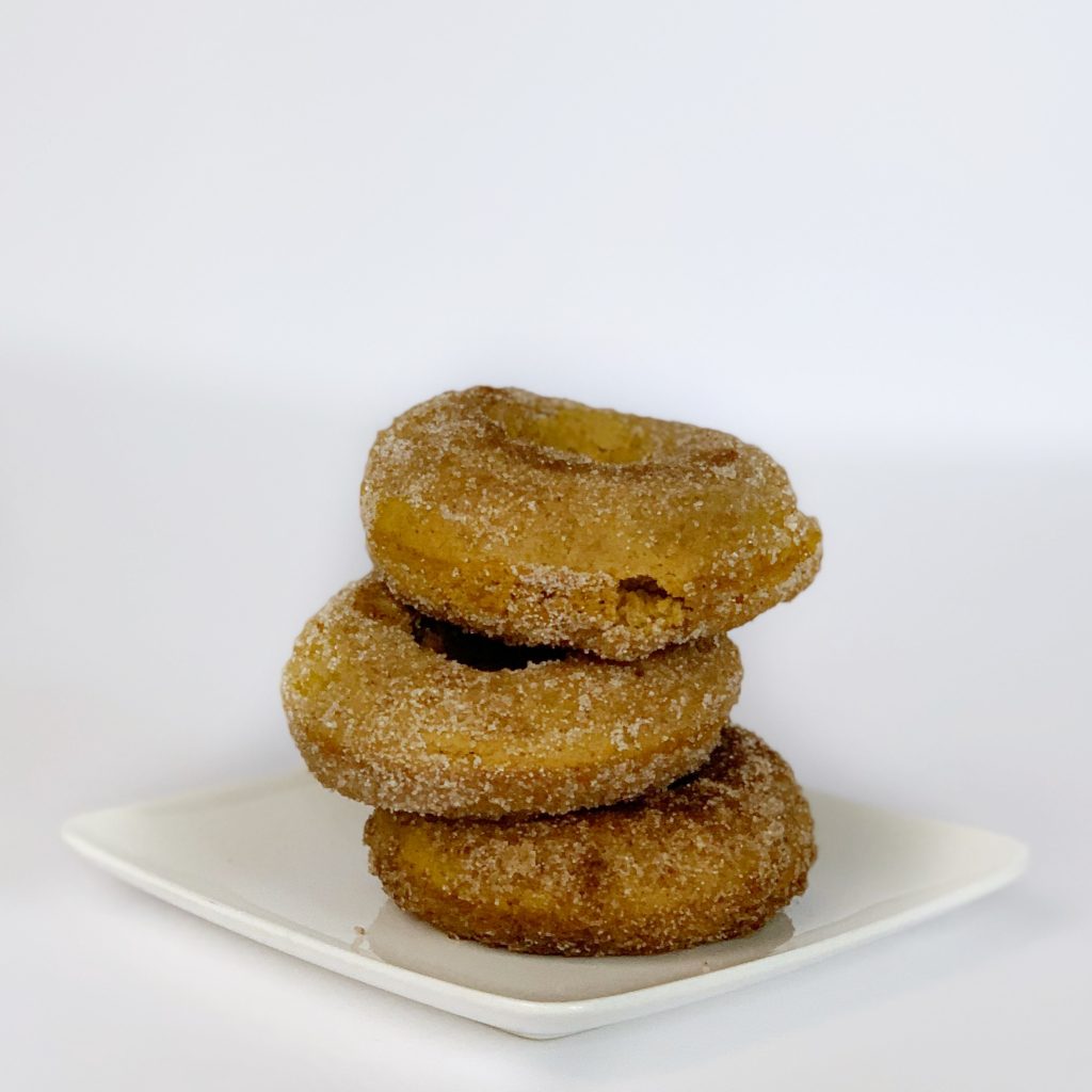 a stack of three pumpkin spiced donuts on a plate